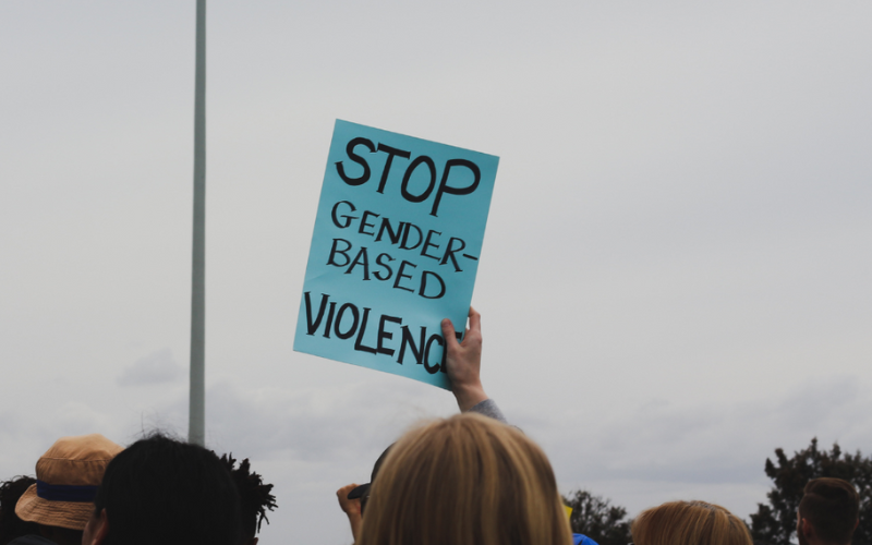 A person holds up a sign that reads: stop gender-based violence.