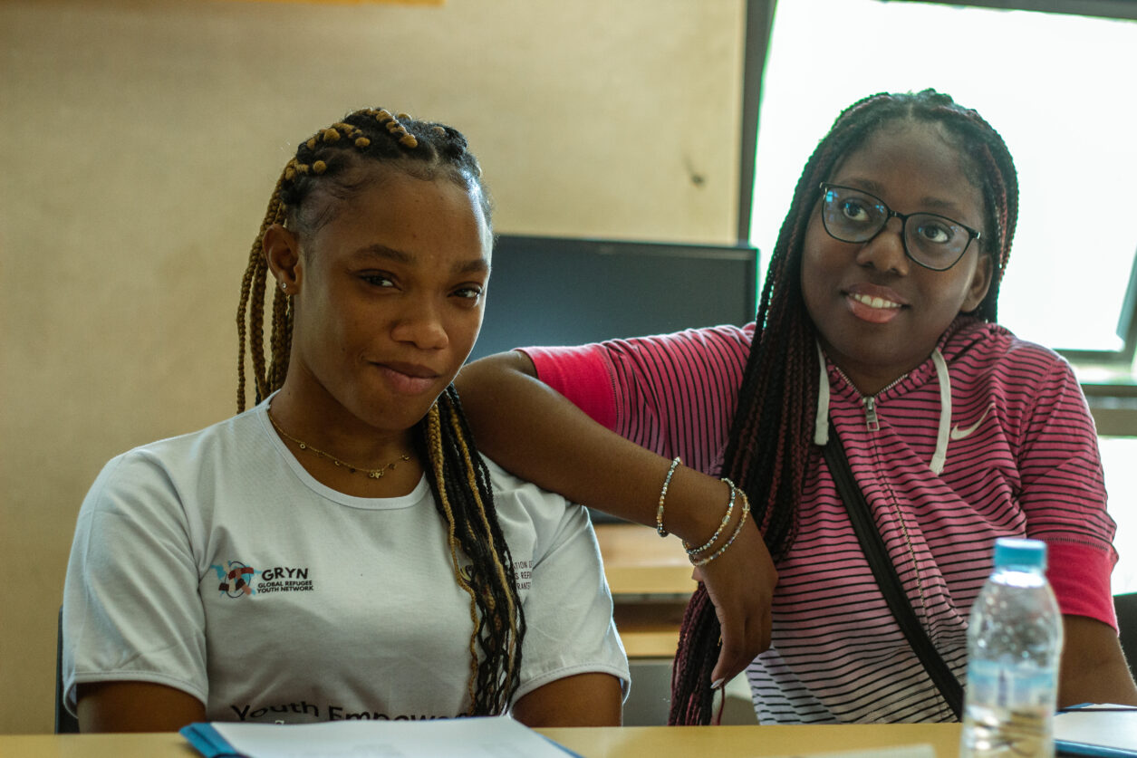 Two girls from the Global Refugee Youth Network sit together